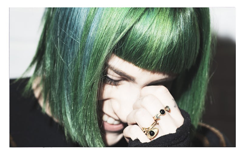 Girl with green hair smiling and looking down 