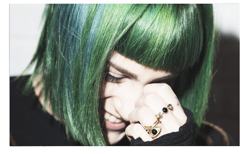 Girl with green hair smiling and looking down 