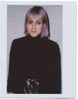 Girl with short violet hair and bangs wearing a black turtleneck