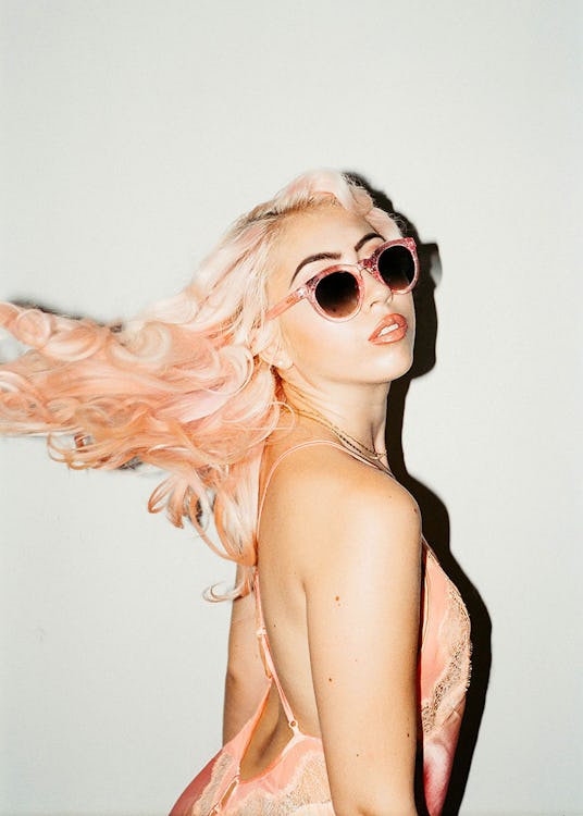 Model with pink hair posing for a photo with pink Crap Eyewear sunglasses