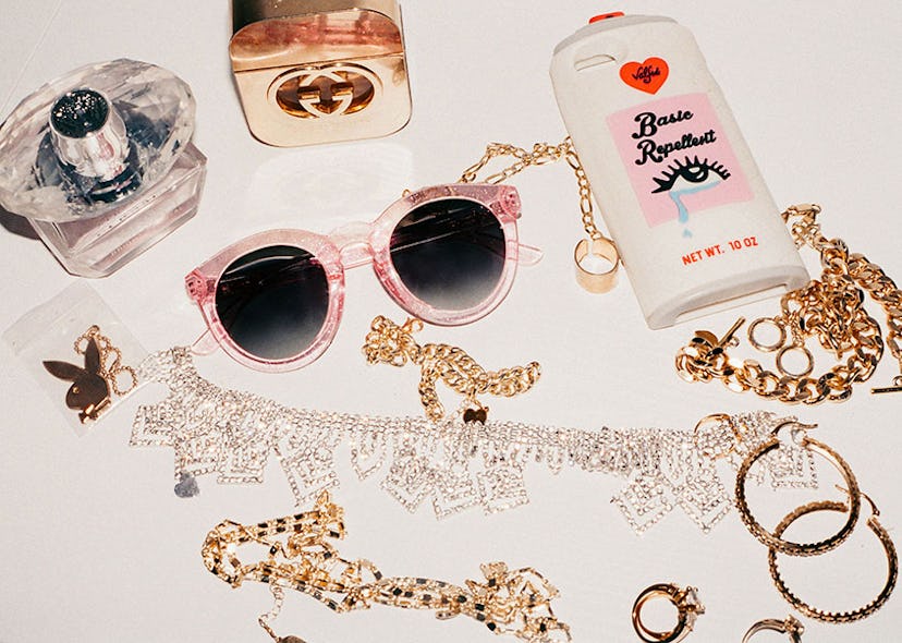 Pink Crap Eyewear sunglasses rings surrounded by a neckless, earrings, a phone case, a Gucci perfume...