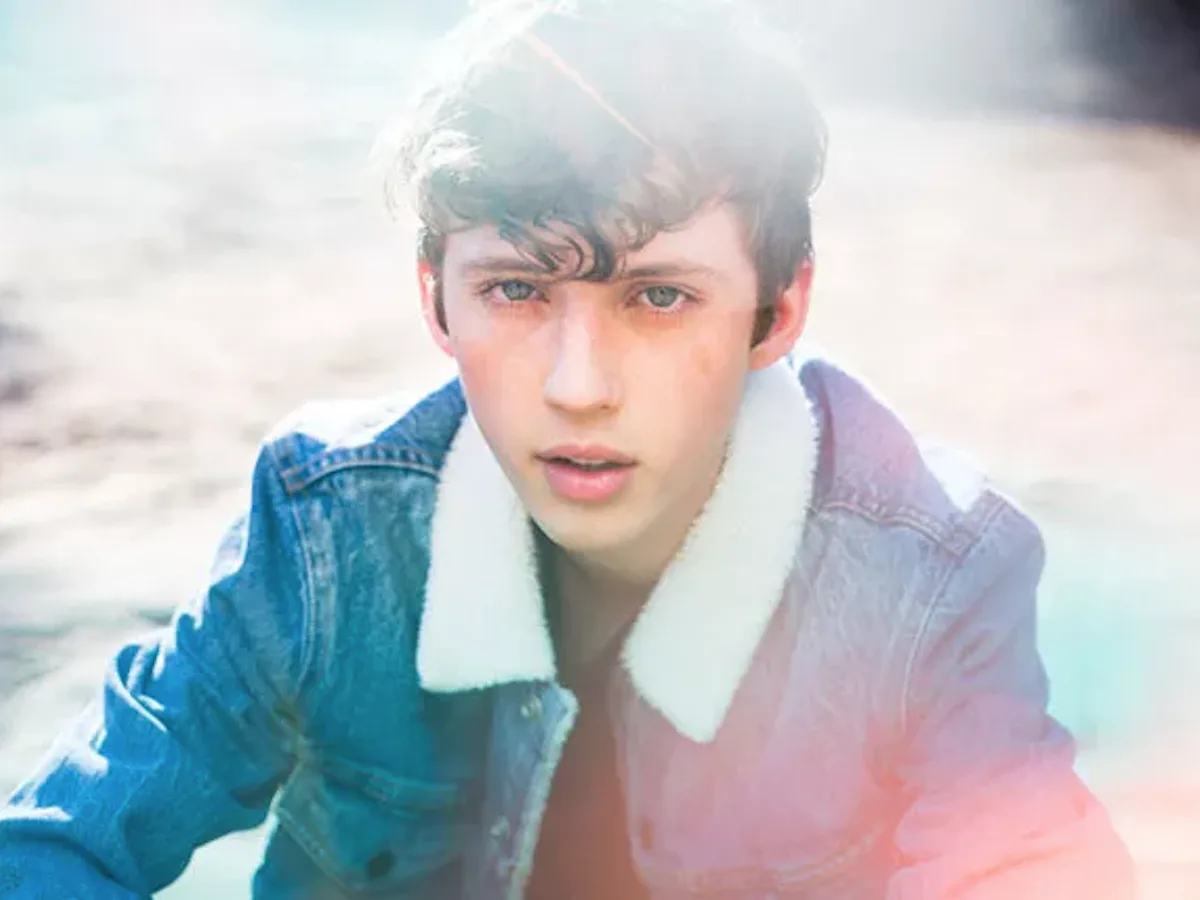Young Troye Sivan in a softly lit denim jacket in the WILD era