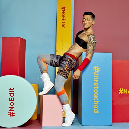 A male model with red lines under his eyes posing next to wooden shapes with hashtags