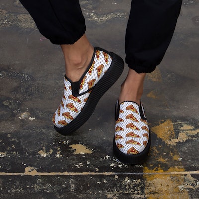 White and black slip-on creeper shoes with pizza slice print and a white surface with small black do...