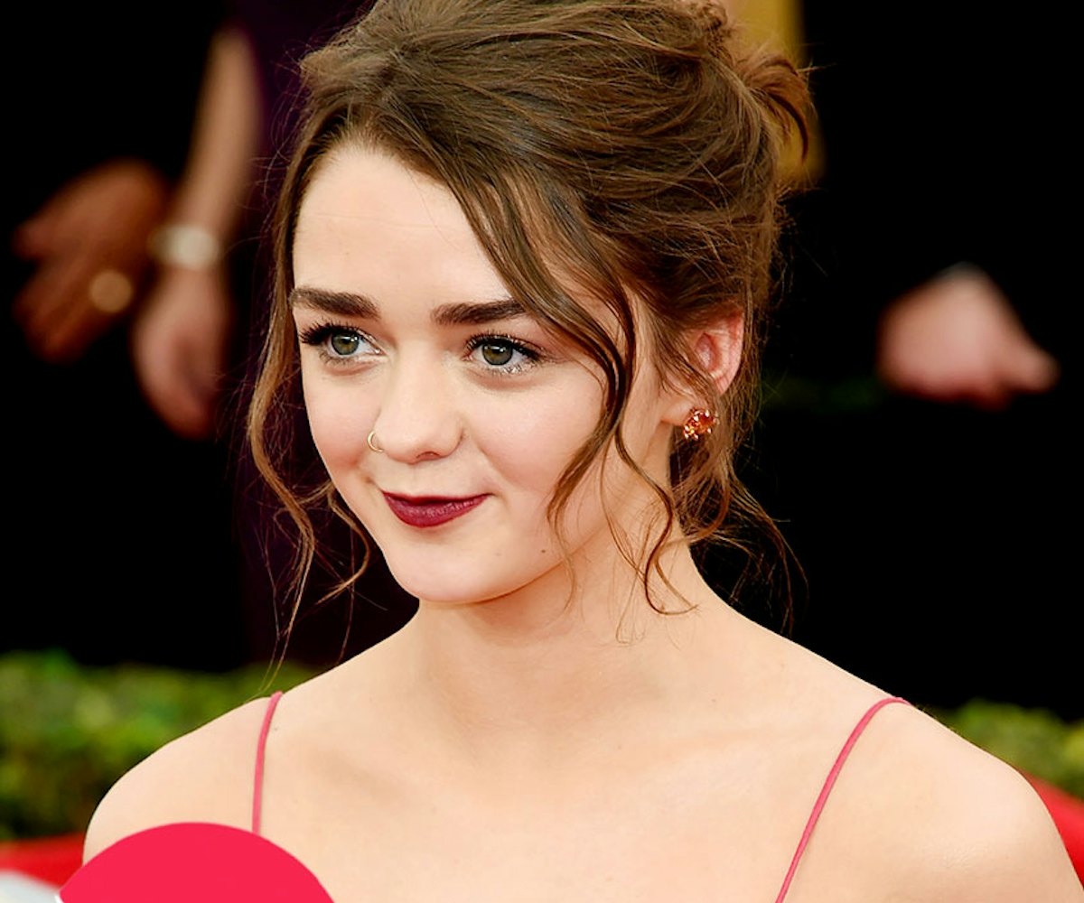 Maisie Williams in a red dress with her hair in a bun