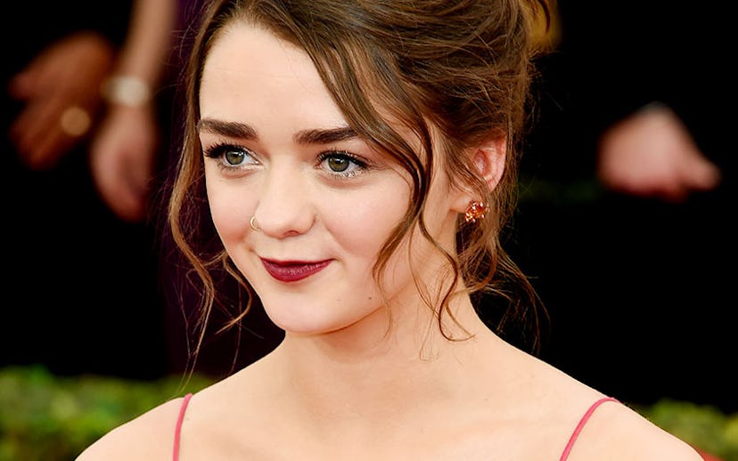 Maisie Williams in a red dress with her hair in a bun