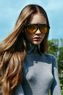 Model posing in a grey dress by Lacoste and nite shift sunglasses by Crap Eyewear