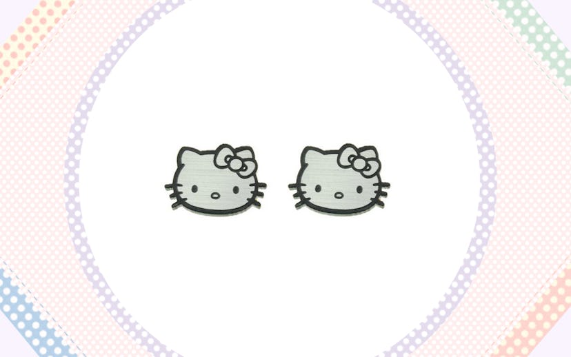 Two grey Hello kitty earrings on a pastel background