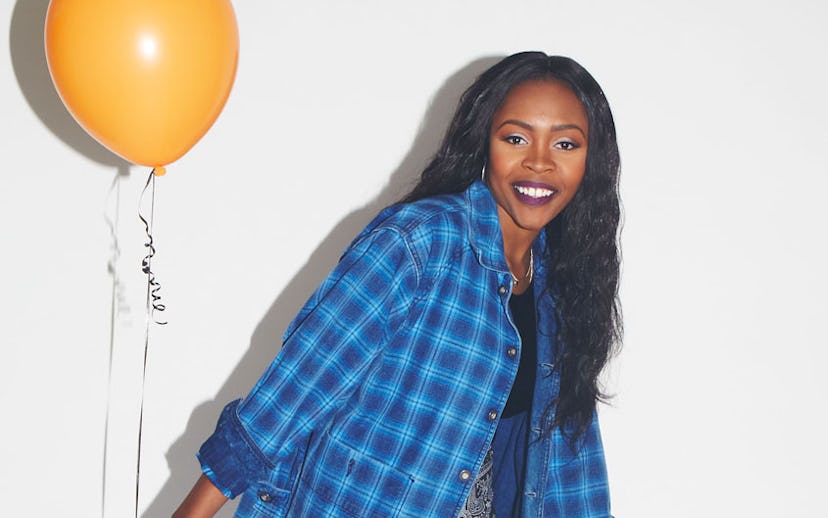 Tink in a blue plaid shirt holding an orange balloon