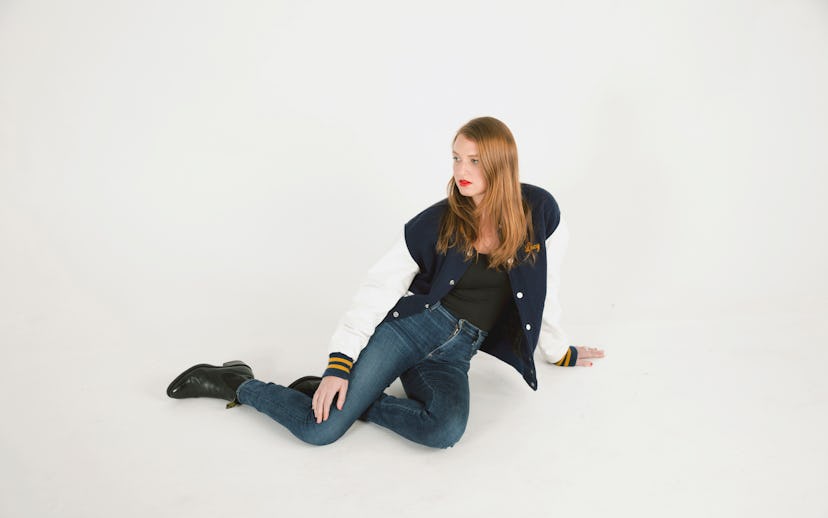 Lily McQueen posing in jeans and a bomber jacket with a red lip
