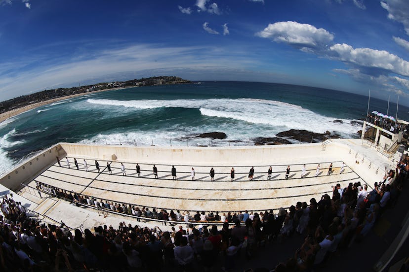 Fisheye lens picture of models standing in a line on a platform next to the sea