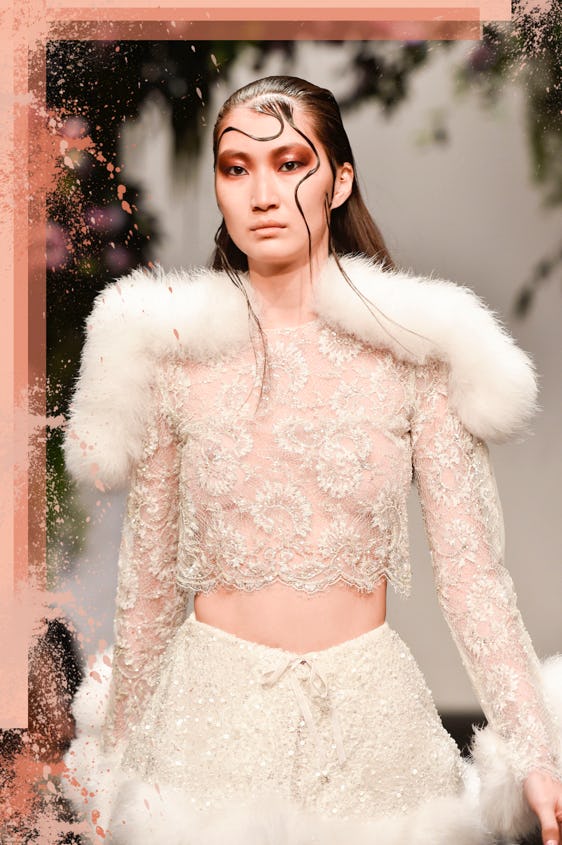 Female model with slicked back hair wearing an off-white, seethrough, lace top and a glittery skirt ...