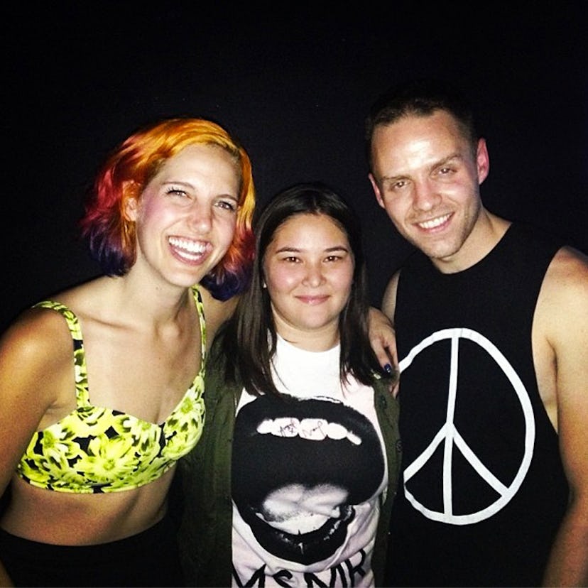 Two women and one man posing for a photo at a concert at the Nylon music tour