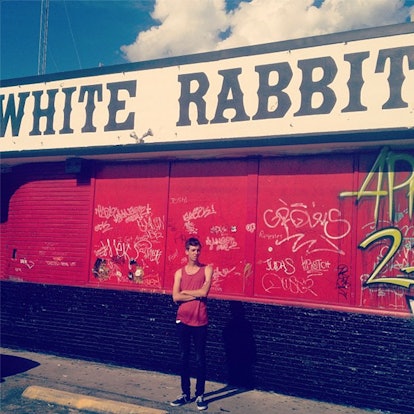 A man standing in front of a red building with a "white rabbit" sign