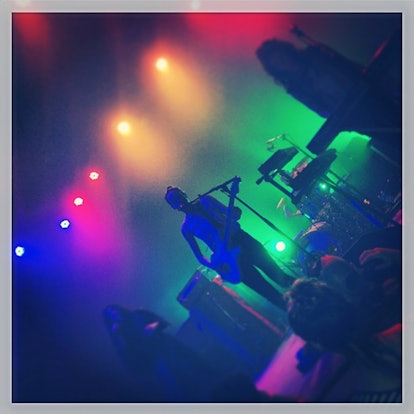 An artist playing a guitar while surrounded by orange, red and green lights