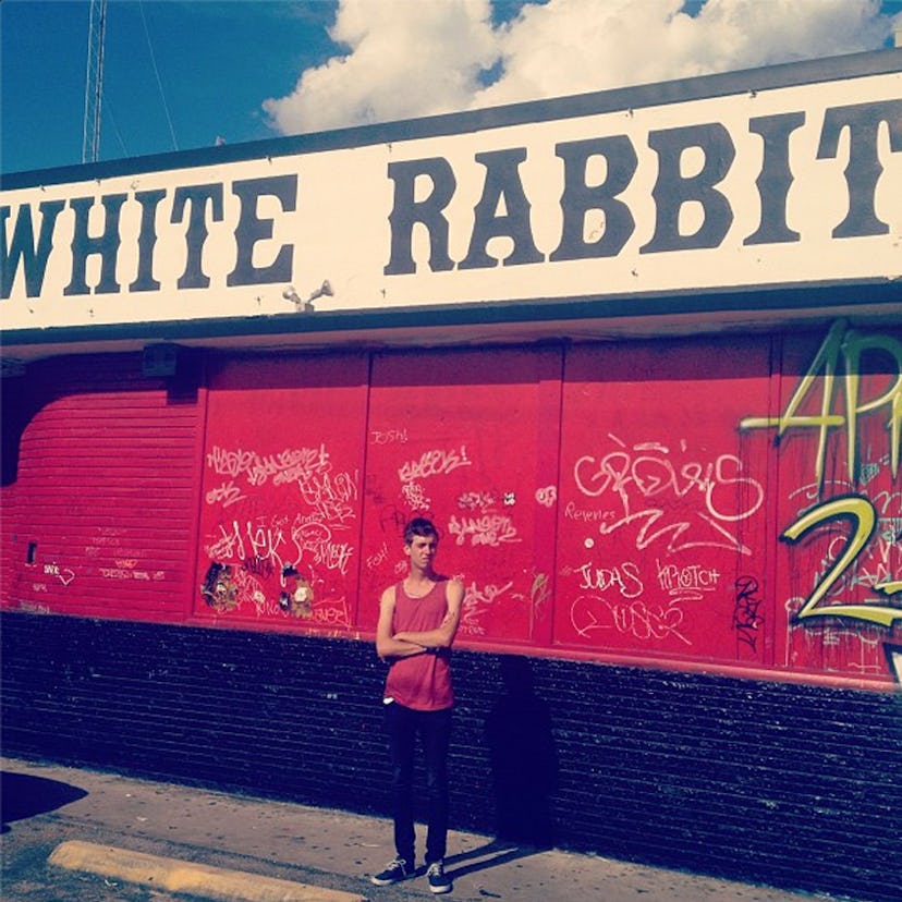 A man psoing in front of a red building with a sign that has "white rabbit" text