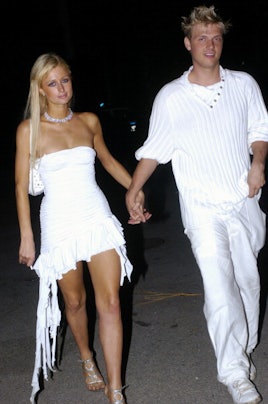 Paris Hilton and Nick Carter both in white combinations walking while holding hands