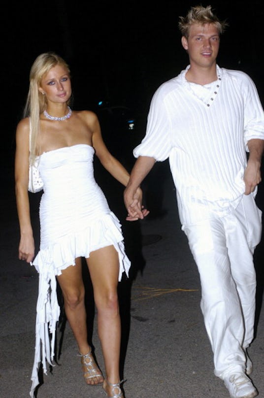 Paris Hilton and Nick Carter both in white combinations walking while holding hands