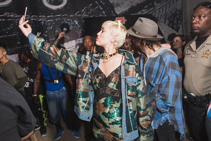 Miley Cyrus in a camouflage combination taking a selfie