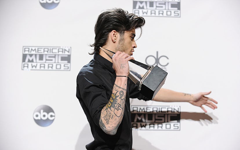 Zayn Malik wearing a black shirt while holding an American Music award