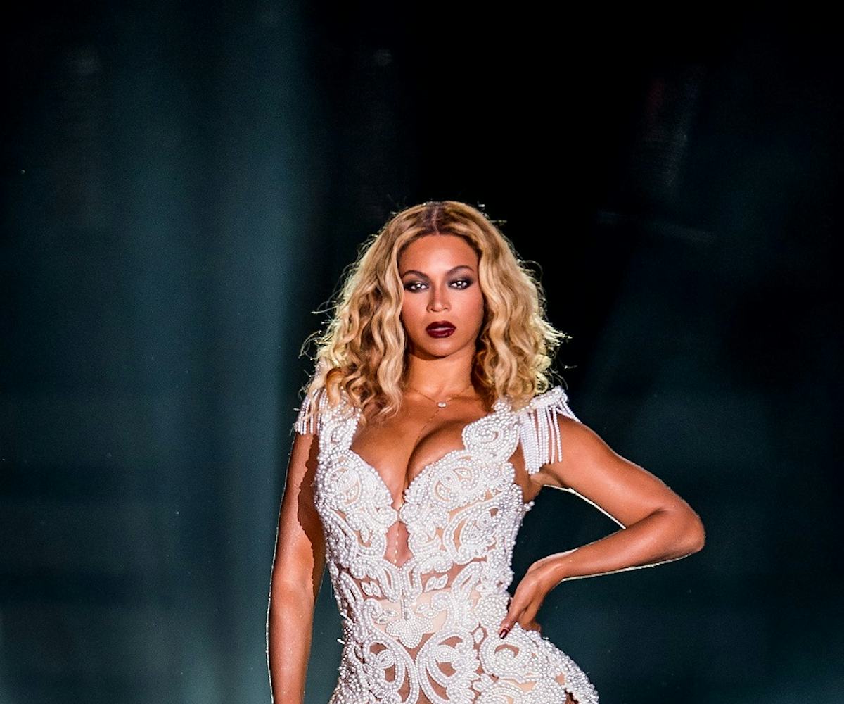 Beyonce in a short lace, white bodysuit with strong make-up, including dark red lipstick