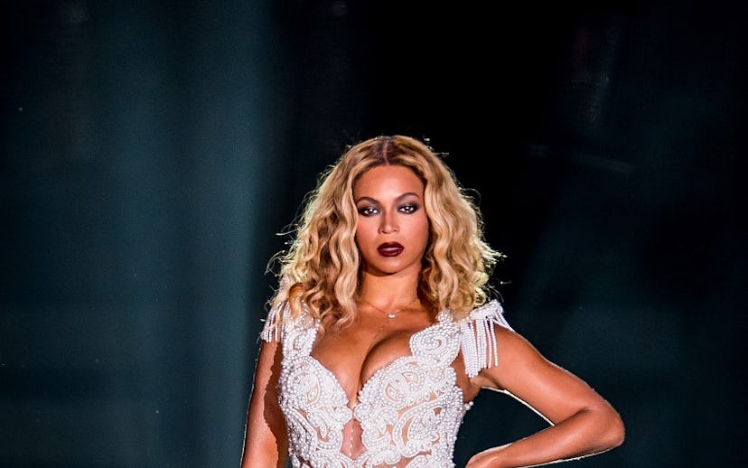 Beyonce in a short lace, white bodysuit with strong make-up, including dark red lipstick