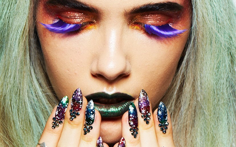 A model with long blue eyelashes, heavy makeup, long turquoise hair with butterfly hair clips.
