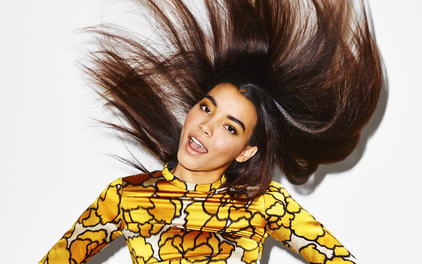 A girl in a yellow dress with a glowing face makeup and shiny hair.