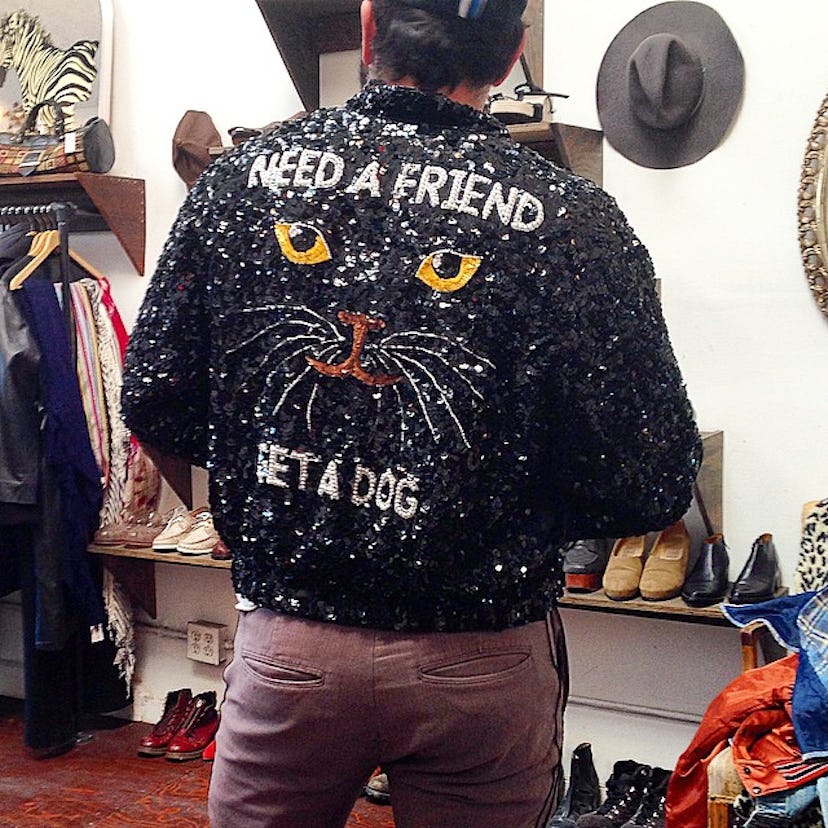Man wearing a sweater with a cats face that says to pet a dog if you need a friends