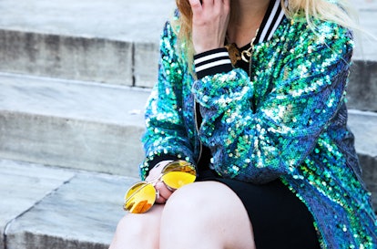Monica Barleycorn sitting in Jaded London's mermaid sequin bomber jacket while holding Coco & Breezy...