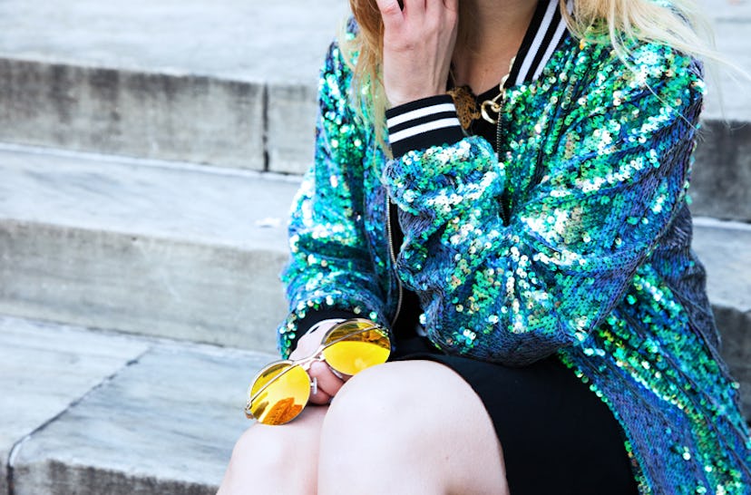 Monica Barleycorn sitting in Jaded London's mermaid sequin bomber jacket while holding Coco & Breezy...