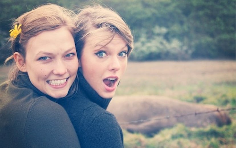 Karlie Kloss in a brown turtleneck shirt hugging Taylor Swift in a black turtleneck shirt from her b...