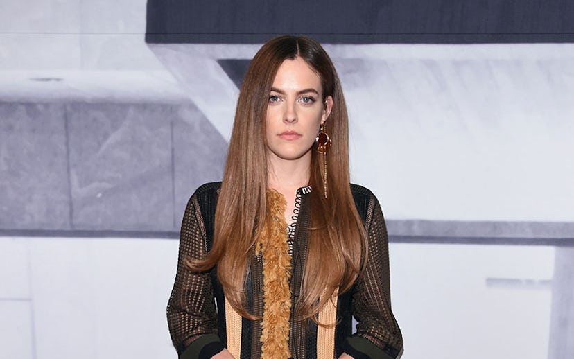 Riley Keough posing with straight brown hair and in a sheer ‘70s-style mini dress paired with patent...