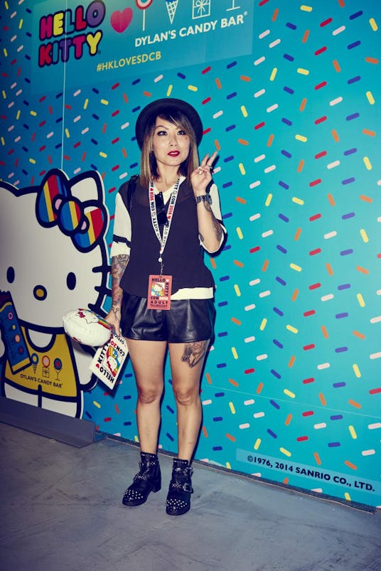 A young lady with a black fedora hat dressed in Hello Kitty style