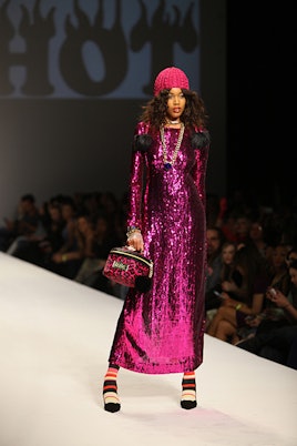 Top Model contestant walking down a runway while wearing a long sparkling purple dress