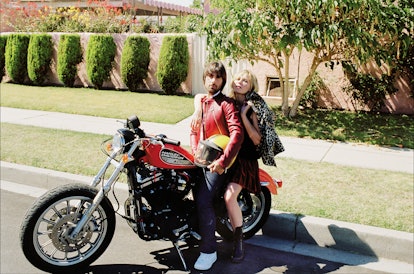 Actor Jason Schwartzman in a red leather jacket and Kirsten Dunst sitting on a red motorcycle