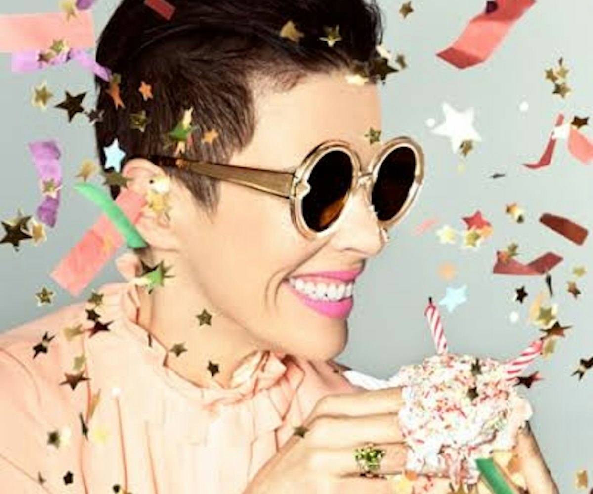 A woman smiling in sunglasses with confetti around her