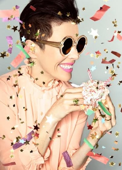 A woman smiling in sunglasses with confetti around her