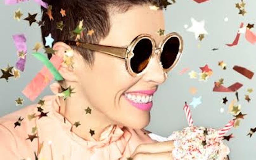 A woman in Karen Walker sunglasses smiling with confetti around her