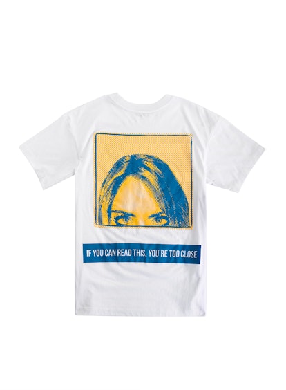 White t-shirt with a yellow box of a woman looking and blue rectangle containing text from the DKNY ...