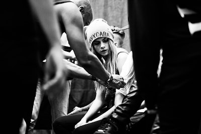 English model and actress Cara Delevingne wearing a beanie while sitting down in a black and white p...