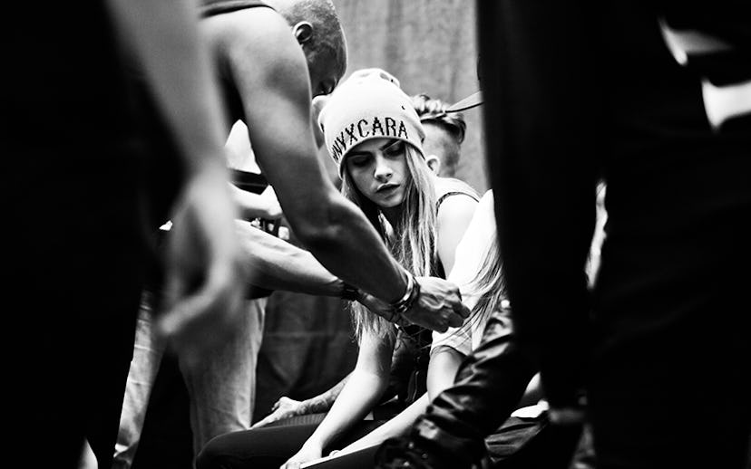 Cara Delevingne wearing a beanie while sitting down in a black and white photo