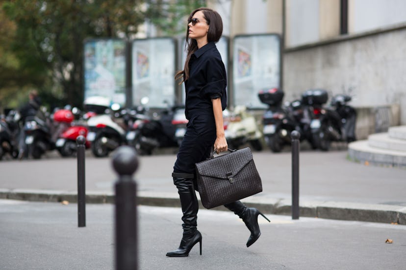 Businesswoman with black shoes and coat walking with a suitcase