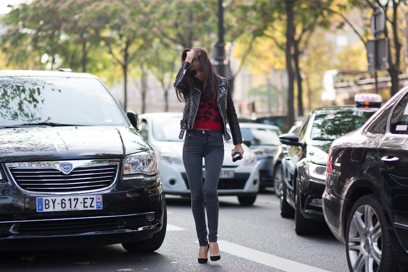 Young girl walking through a traffic street in black jacket and slim fit pants