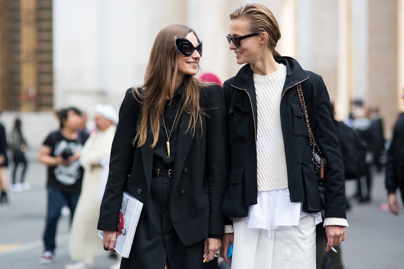 Two female friends walking through the Paris streets and wearing black street style jackets
