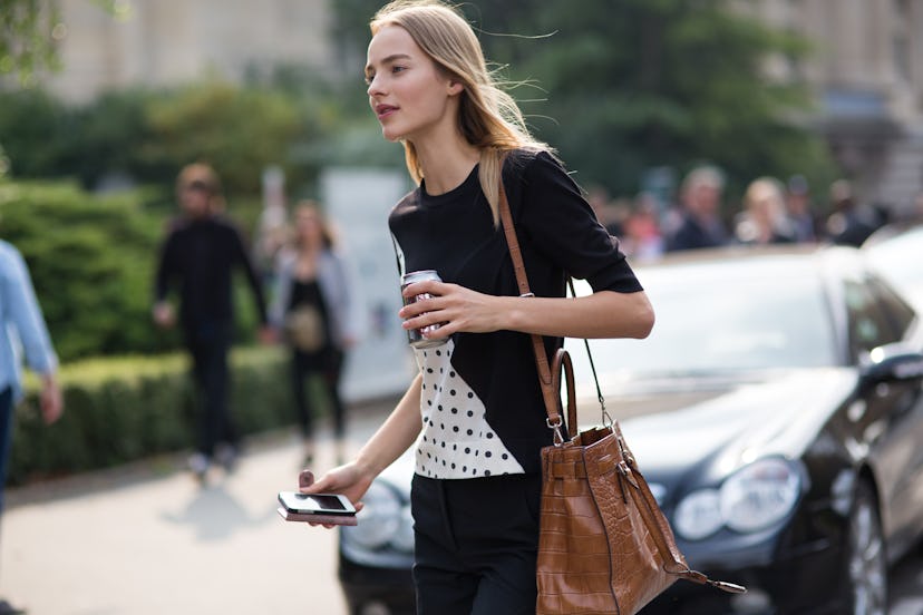 Blonde lady drinks a coffee to go while walking through a Paris street