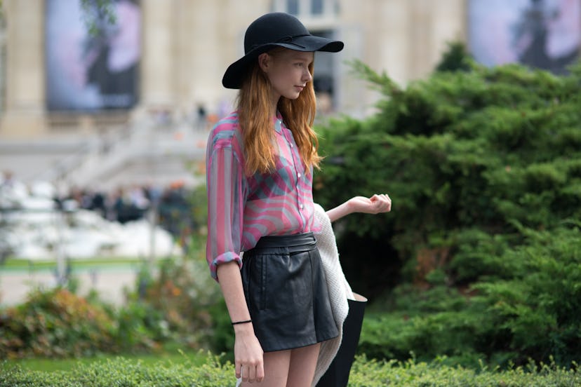 Young girl in a pink button-up shirt and a black hat