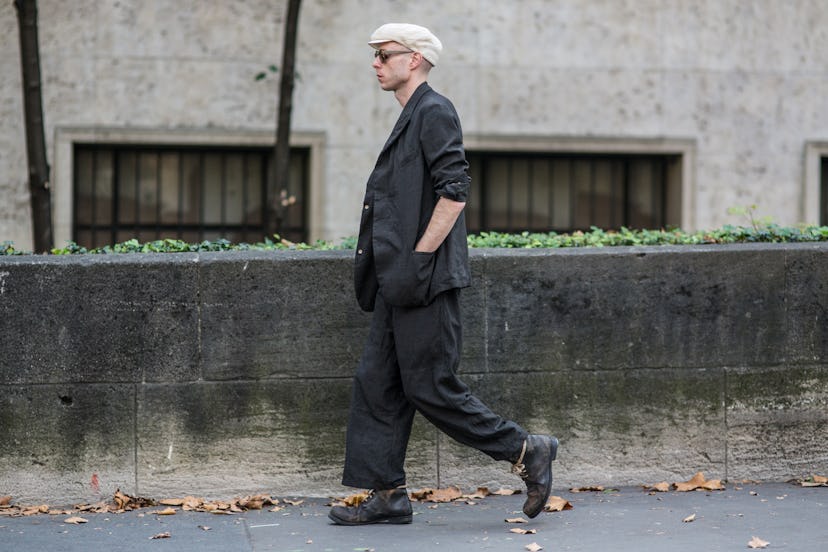 A man wearing a black blazer and baggy pants in a Paris street