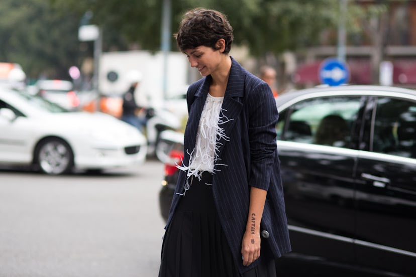 A brunette woman wearing a black jacket and white shirt on the streets of Milan