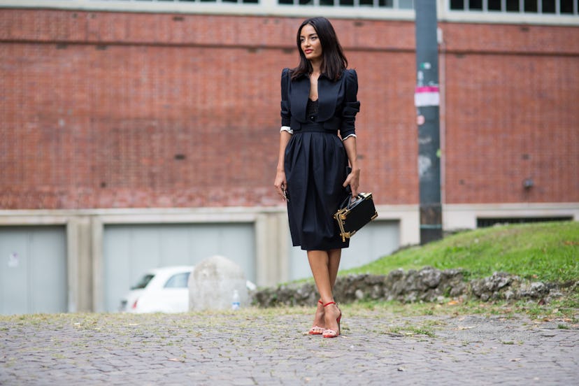 A Black-haired woman wearing a black dress and red high-heeled sandals on the streets of Milan